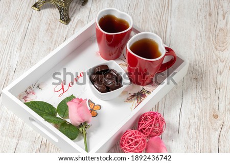 Two heart-shaped cups and chocolate on a white rustic tray.Breakfast for lovers. Valentine's Day. Postcard.