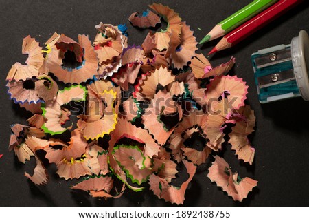Opened colored wooden dry crayons with sharpener on black background close-up