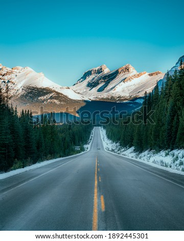 An open road shot in Banff National Park with the Rocky Mountains in the back