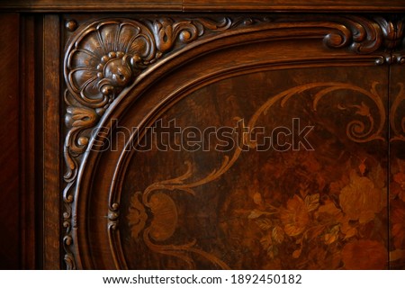 Carved wooden chest of drawers. Close-up photo of vintage furniture with elegant ornamental pattern from past.