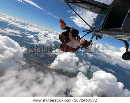 Young woman skydiver jumping from the plane performing front loopings. Fearless and confident.  Royalty-Free Stock Photo #1892469592