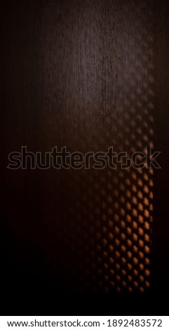 orange light pattern on a dark brown wood door 