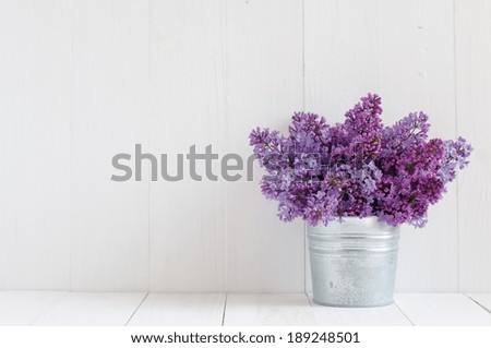 Bouquet of beautiful spring flowers of lilac in a vase on a white vintage wooden board, home decor in a rustic style Royalty-Free Stock Photo #189248501