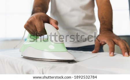 A man's hand using an iron. Iron the garment to make it smooth. Pictures about housework