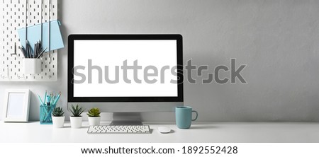 Panoramic photo of stylish workspace with mock up computer and office supplies gadget. Blank screen and copy space for graphic display montage. Royalty-Free Stock Photo #1892552428