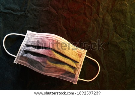 Medical mask or surgical earloop mask with red-yellow light on Black paper background                               