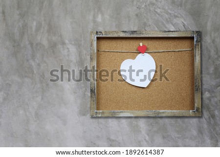 Empty heart shape and wooden photo frame on gray wall for valentines day design.