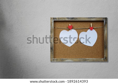 Empty heart shape and wooden photo frame on gray wall for valentines day design.