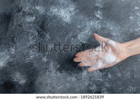 Hand with soap bubbles showing hand on marble background