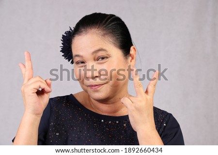 Elderly senor Asian woman posing facial expression happy smile v sign finger