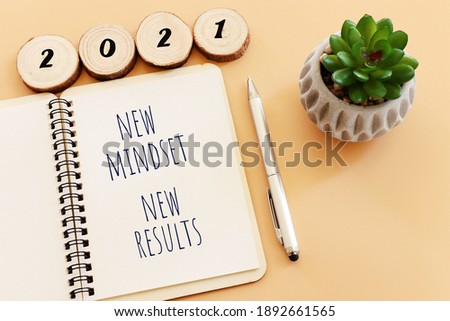 top view image of table with open notebook and the text new mindset new results. success and personal development concept