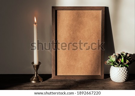 Retro interior with photo frame mockup on a wooden brown shelf, a plant in a white pot and a burning candle. Space for text, copy space.