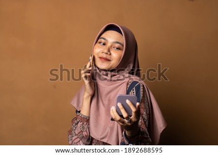 Portrait of beautiful asian woman applying powder puff at cheek makeup of cosmetic on gold background.