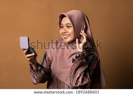 Portrait of beautiful asian woman applying powder puff at cheek makeup of cosmetic isolated on gold background.