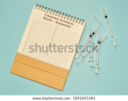 September treatment schedule calendar and disposable injection syringe on blue background
