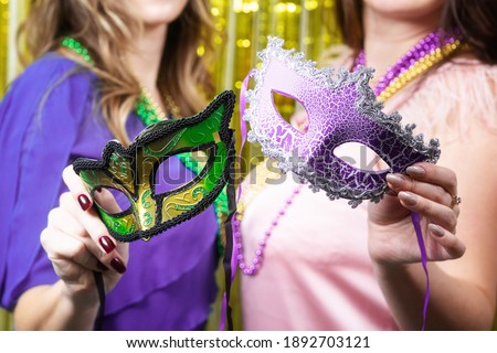 Mardi gras party. Women hold a carnival masks on the golden festive background.