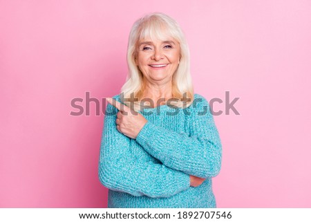 Photo of old funny lady direct forefinger empty space wear blue pullover isolated pink color background