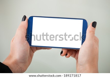 Cropped image of businesswoman's hand holding smartphone in office