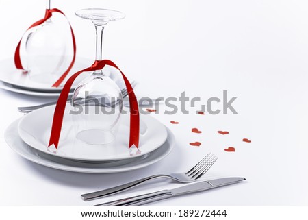 Wine glasses turned upside down with red decoration as background for invitation and menu