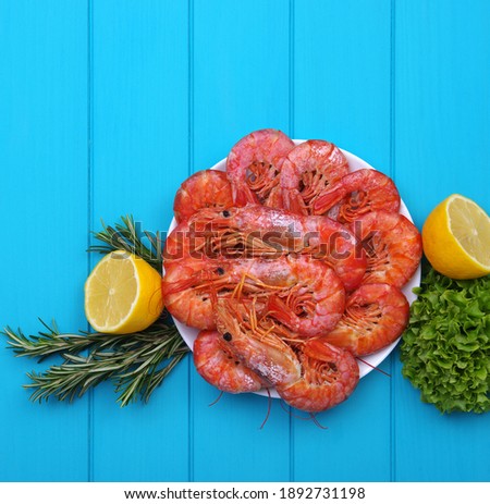 Cooked shrimps with lemon and spices. Seafood served on wooden table. Top view. Close-up