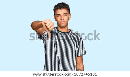 Young handsome african american man wearing casual clothes looking unhappy and angry showing rejection and negative with thumbs down gesture. bad expression. 