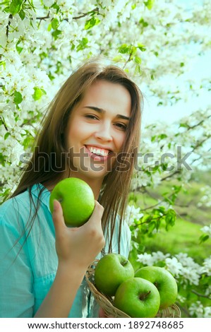 Portrait of face young latin hispanic woman holding apple on Spring blooming apple tree background. summer nature. spring time season.Pretty in establishment of branches of a blossoming apple