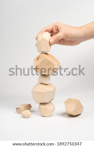 Tumi-ishi puzzle game. A woman or a girl places her hand on another block of wood on top of an unstable tower. The process of the game. Stones for Rock Balance. Royalty-Free Stock Photo #1892750347