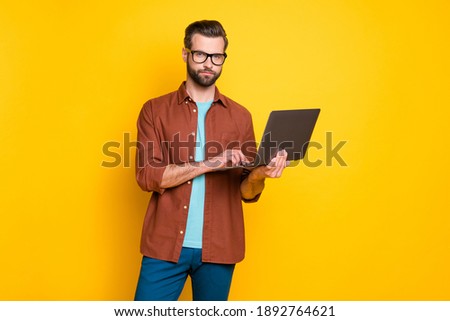 Photo of young serious focused minded handsome man businessman boss working in laptop isolated on yellow color background