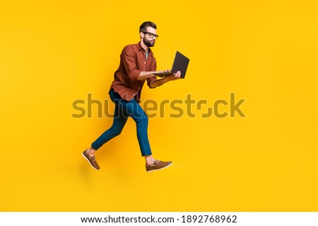 Full length body size photo of freelancer in glasses working on computer typing texting isolated on vivid yellow color background