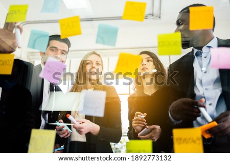 Group of successful business teamwork. Brainstorm meeting with colorful sticky paper note on glass wall for new ideas. Using agile methodology and do business. Brainstorming in a tech start-up office. Royalty-Free Stock Photo #1892773132