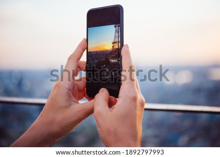 Person is aking a picture of the evening city view with their smartphone