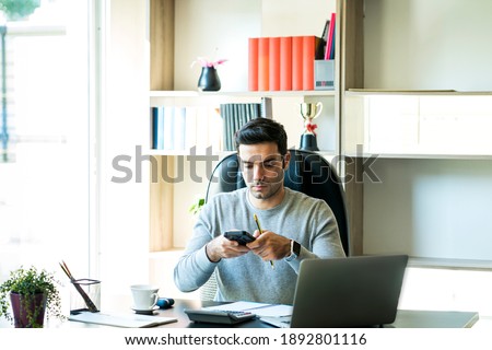 Young businessmen are using mobile phones to scan documents to send by app. Man holding and using his mobile phone. Work from home. Royalty-Free Stock Photo #1892801116