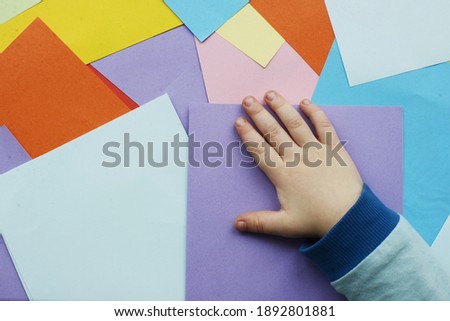 kid hand on colourful paper background