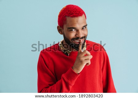 Happy funky young african wearing street clothes over isolated background, showing silence gesture