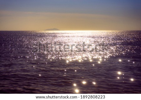 Glittery golden sea water during sunset with the sky looking blue and orange Royalty-Free Stock Photo #1892808223