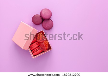 Valentine's day concept. Pink box with marmalade and macaroons and a beautiful rose on a pink background