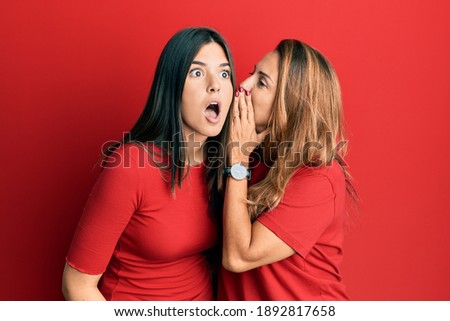 Hispanic family of mother and daughter wearing casual clothes over red background hand on mouth telling secret rumor, whispering malicious talk conversation  Royalty-Free Stock Photo #1892817658