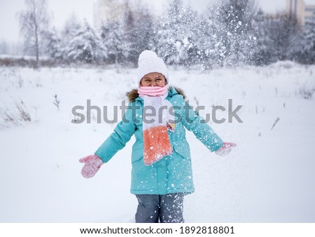 Girl baby in nature in winter plays with snow