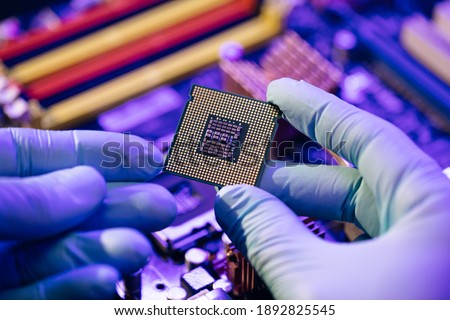Laboratory technician holds a powerful processor in his hands. CPU computer processor shallow focus. CPU socket of the computer's motherboard. Concept of computer, motherboard, hardware and technology Royalty-Free Stock Photo #1892825545