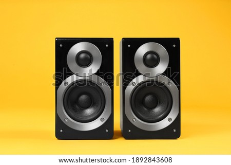 Modern powerful audio speakers on yellow background Royalty-Free Stock Photo #1892843608
