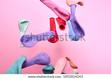 Multicolored not inflated balloons thrown into the air on a pink background, creative background.