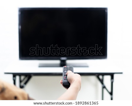 Hand holding the remote to turn on the TV