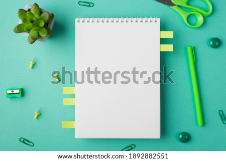 Flat lay mock up above overhead view photo image of clear textbook with office supplies and green succulent plant isolated green desk backdrop