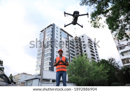 Builder operating drone with remote control at construction site. Aerial survey