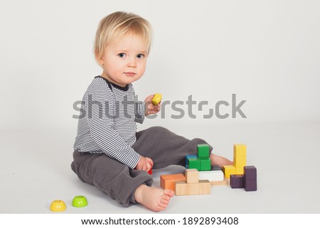 Little baby boy is playing with colourfull wooden block isolated on white background. Education and learn game concept with copy space.