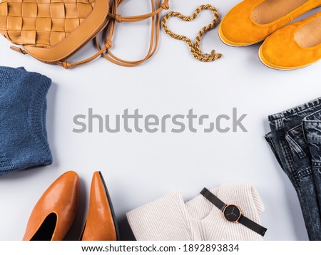 Fashion autumn winter lady outfit items frame flat lay. Trendy yellow, blue, gray clothes and accessories - shoes, sweaters, jeans, bags.
