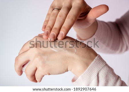 The girl smears a drop of cream on her hand with her finger. beauty of hands. Skin care.