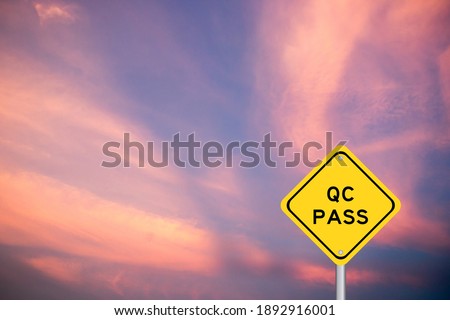Yellow transportation sign with word QC (Quality Control) pass on violet sky background