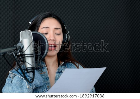 Asian female singer singing in a recording studio. Female singer singing and playing guitar. Royalty-Free Stock Photo #1892917036