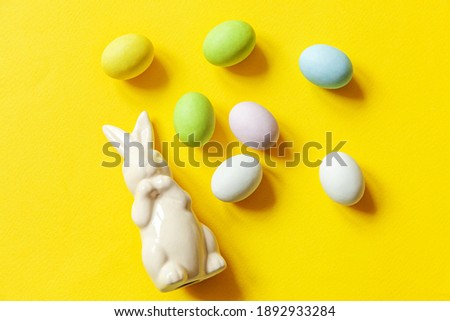 Happy Easter concept. Preparation for holiday. Easter candy chocolate eggs sweets and bunny toy isolated on trendy yellow background. Simple minimalism flat lay top view copy space